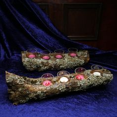 two logs with candles in them on a blue cloth