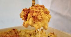 a fork full of macaroni and cheese being lifted from a bowl with other food