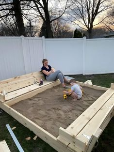 two children playing in an outdoor sandbox