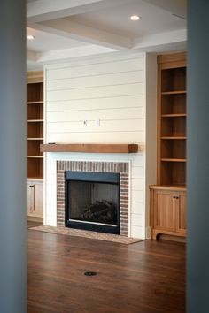 an empty living room with a fireplace and built in bookshelves on either side