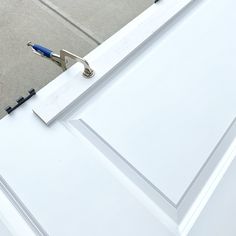 a pair of pliers are attached to the side of a white door that is partially open