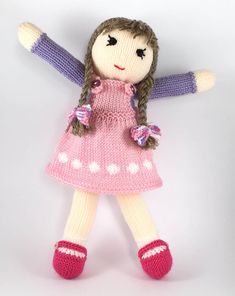 a knitted doll with brown hair and pink dress holding her arms in the air