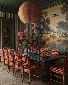 a dining room table with red and white striped chairs next to a large painting on the wall