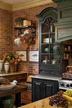 an old fashioned kitchen with brick walls and black cabinetry, surrounded by fruit on the counter