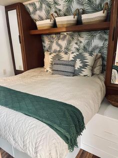 a bed with two baskets on the headboard and one shelf above it that is filled with pillows