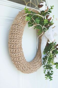 a wreath with cotton and greenery hanging on the front door to give it a rustic feel