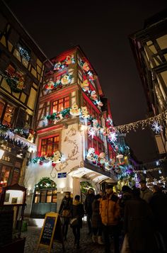 people are standing in front of a building decorated with christmas lights