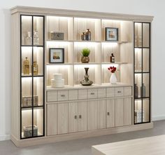 an empty room with shelves and vases on the wall next to a table in front of it