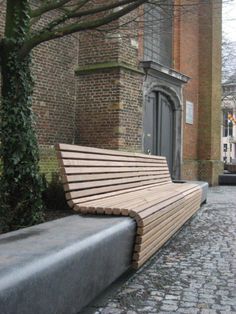 a wooden bench sitting on top of a cobblestone street next to a tall brick building