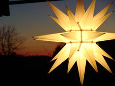 a lighted star hanging from the side of a building