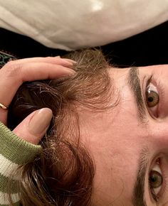 a close up of a person cutting another persons hair with scissors and an object in the background