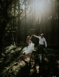 a bride and groom dancing in the woods