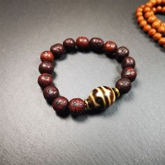 This unique Dalo Dzi bracelet combines the mysterious and unique qualities of the tiger tooth dalo dzi and 15 old bodhi seed beads,giving it a distinct feel.It is brown in color and has a circumference of approximately 7 inches, suitable for most wrist sizes.This bracelet can be worn not only as a fashionable accessory but also holds cultural and religious significance.Dzi beads are precious jewelry from Tibetan culture which are believed to possess the power of bringing good fortune to the owne Spiritual Brown Beaded Bracelets, Unique Hand-strung Brown Beaded Bracelets, Spiritual Brown Bracelets With Wooden Beads, Spiritual Brown Stretch Bracelet With 8mm Beads, Brown Rosary Bracelet With 8mm Beads For Meditation, Hand-strung Brown Beaded Bracelets For Meditation, Spiritual Brown Beaded Bracelets With Wooden Beads, Brown Hand-strung Beaded Bracelets For Meditation, Brown Rosary Bracelet For Meditation