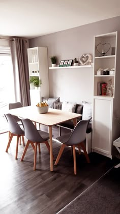 a dining room table and chairs in front of a bookshelf with shelves on the wall