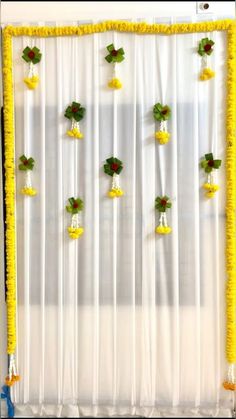 the wall is decorated with yellow flowers and green leaves on white sheer curtains, along with small bells