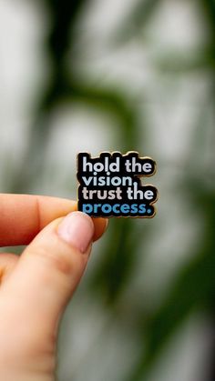 a person holding up a sticker that says hold the vision, trust the process