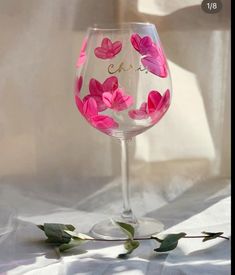 a wine glass with pink flowers painted on it