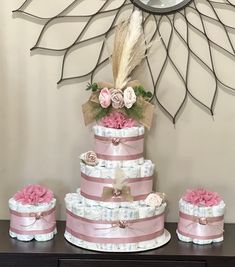 a three tiered pink and white cake with matching diapers