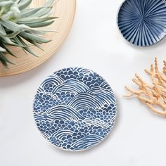 two plates with blue designs on them next to some corals and a pineapple