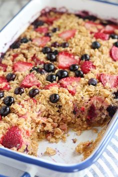 an oatmeal dessert with strawberries and blueberries on top is ready to be eaten