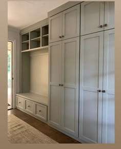 an empty room with white cupboards and drawers on the wall next to a door