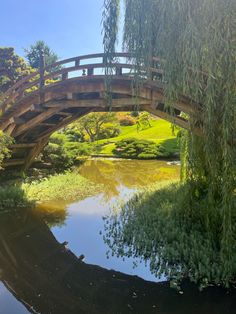 a wooden bridge over a small pond in a park