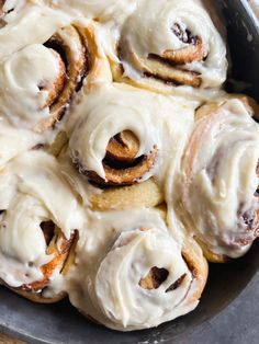 a pan filled with cinnamon rolls covered in icing