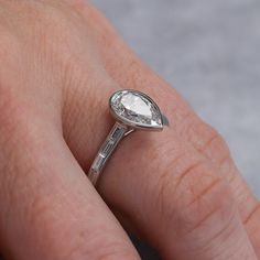 a woman's hand with a diamond ring on top of her finger, showing the center stone