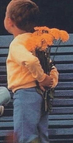 a young boy is holding flowers on a bench