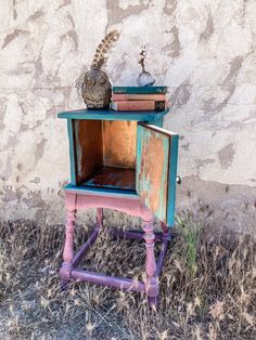 an old wooden table with books and a bird on top