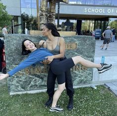 two young women are posing in front of a statue with their arms around each other