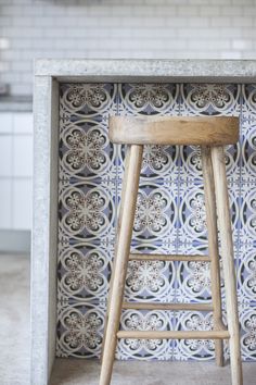 a wooden stool sitting in front of a tiled counter