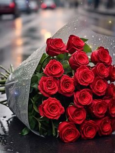 a bouquet of red roses sitting on top of a wet table