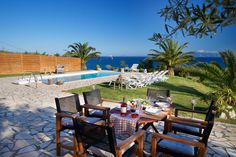 an outdoor dining area with chairs and table next to the pool, overlooking the ocean