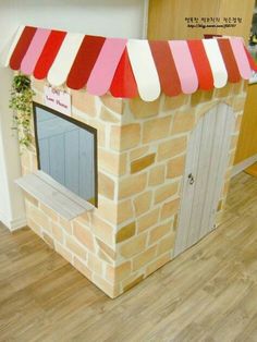 a cardboard house made to look like a brick building with red and white awnings