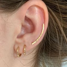 These ear climber earrings are made of 18k gold-plated silver. The hammered wire with a fine texture is slightly curved following the contour of the ear. 🌼 Nickel-free. Made from ethical and recycled 950 solid silver. MEASUREMENTS: ✔️ Length: 24 mm. ✔️ Width: 1.7 mm. ✔️ Ear wire: 0.9 mm. They are very comfortable. Simply pass the wire through the ear hole, turn and position it on the natural curve of the ear. Perfect for everyday wear, single or in combination with other earrings. ✔️ Sold alone Gold Ear Crawlers, Ear Sweeps, Ear Wrap Earrings, Ear Cuff Gold, Line Earrings, Gold Ear Climbers, Silver Ear Climbers, Ear Crawler, Ear Crawlers