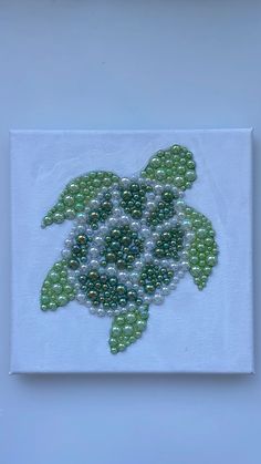 a sea turtle made out of beads on a piece of white paper with blue background