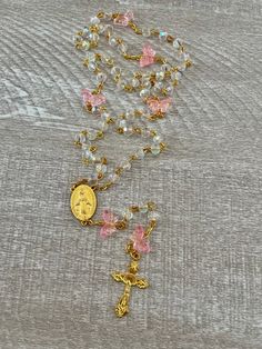 Handcrafted Catholic prayer rosary. Traditional 5 decade chain style rosary. It is made with a delicate gold plated crucifix and matching gold plated Virgin Mary medallion.  Translucent pink butterfly beads and clear faceted iridescent crystal 6mm glass beads.  Each bead is hand placed, turned and connected.  This butterfly garden rosary is beautiful and light weight. Makes a perfect gift.  The rosary is handmade in Florida.  Made with love.  Many Blessings. ♥️ Gold Crucifix Rosary For Jewelry Making, Gold Beaded Crucifix Rosary, Gold Beaded Rosary Bracelet For Healing, Gold Spiritual Rosary With Miraculous Medal, Gold Rosary With 8mm Beads For Healing, Handmade Gold Rosary For Healing, Gold Spiritual Rosary For First Communion, Handmade Gold Healing Rosary, Gold Spiritual Rosary Bracelet For Healing