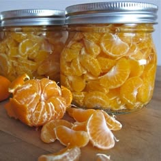 two jars filled with oranges sitting on top of a wooden table