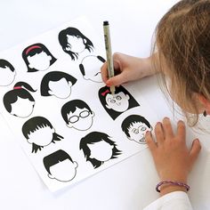 a person is drawing on some paper with their hair cut out to look like the faces of people