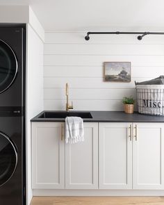 a washer and dryer in a white laundry room with wood flooring on the walls