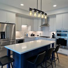 a kitchen with white cabinets and blue island