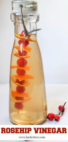 a glass bottle filled with liquid and sliced oranges on top of it next to berries