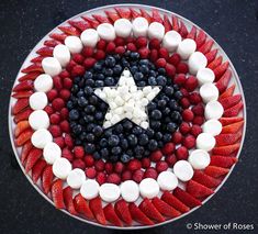 a plate with strawberries, blueberries, and marshmallows arranged in the shape of an american flag