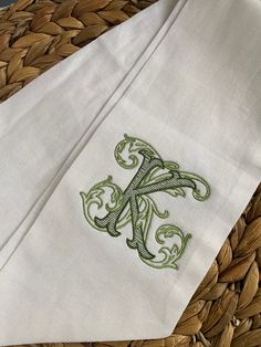 the monogrammed letter k is on top of a white napkin with green embroidery