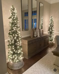 a christmas tree is lit up in front of two mirrors and a dresser with lights on it