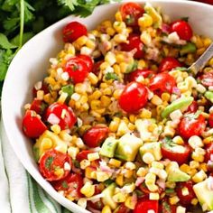 corn salad with tomatoes, avocado and cilantro in a white bowl