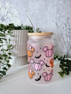 a pink mason jar with halloween pumpkins and bats on it next to some plants