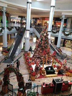 a christmas tree is in the middle of a shopping mall with an escalator