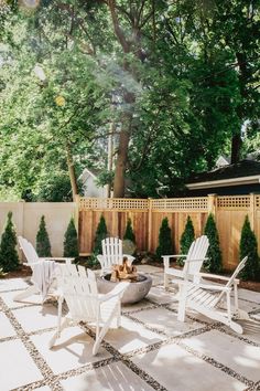 an outdoor patio with white chairs and fire pit in the middle, surrounded by trees